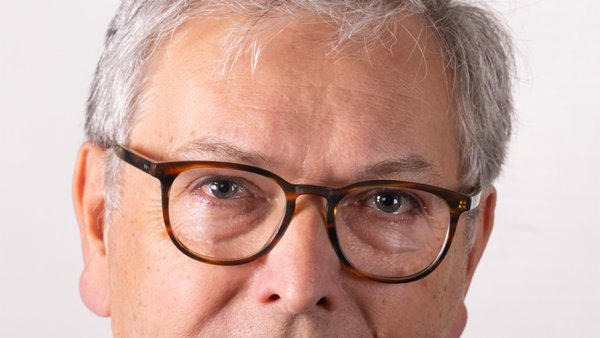 Porträit von einem Mann der Brille, blaues Jackett und Krawatte trägt