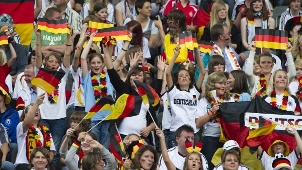 Fussballfans stehend auf der Tribüne mit Deutschland-Flaggen.