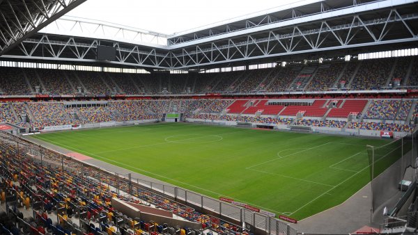 Fußballstadion mit offenen Dach kurz vor einem Spiel, die Tribünen sind größtenteils gefüllt.