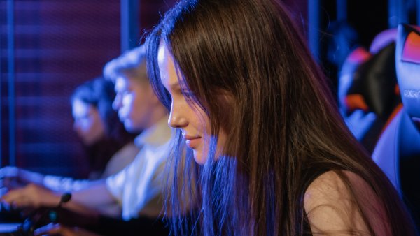 Intensive Konzentration einer Frau beim Gaming in einer lebhaften und wettbewerbsorientierten Umgebung mit lebendiger Beleuchtung.
