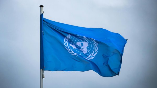 blaue Flagge der UN vor einem bewölkten Hintergrund