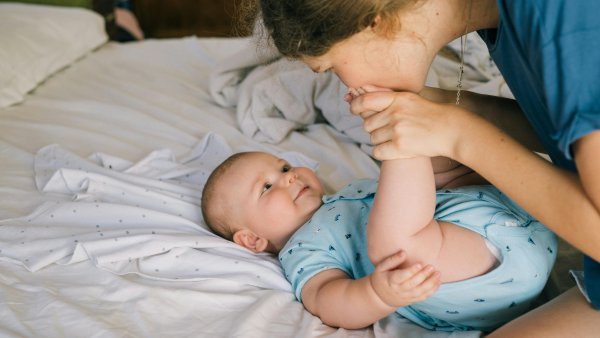 Baby auf dem Wickeltisch mit einer Frau, die ihm den rechten Fuß küsst