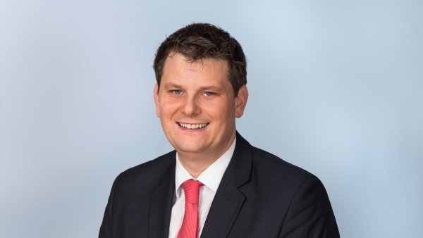 Polonia-Landesbeauftragter Thorsten Klute lächelnd im schwarzen Anzug, weißem Hemd und roter Krawatte.