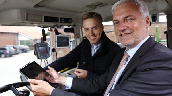 Minister Duin sitzt in einem Traktor mit einem Tablet in der Hand neben Torben Calenberg