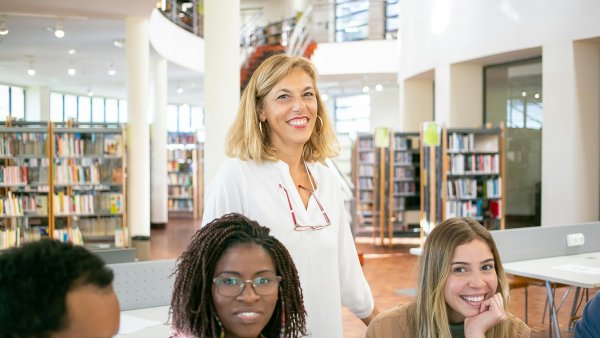 Gruppe von Studierenden mit Professorin in Campus-Bibliothek