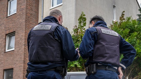 Mitarbeiter des Ordnungsamts stehen vor einem Wohnhaus