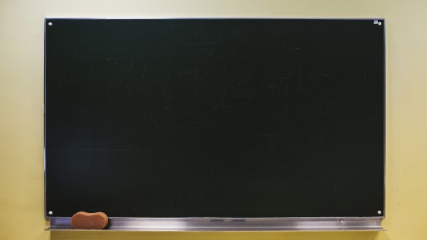 Eine unbeschriebene, schwarze Tafel, in deren Ablage sich links ein brauner Tafelschwamm befindet