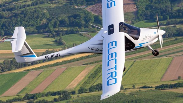 Ein weißes Flugzeug fliegt hoch über einigen Feldern