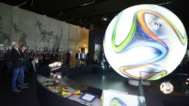 Minister Duin betrachtet ein großen leuchtenden Ball in einer dunklen Museumshalle