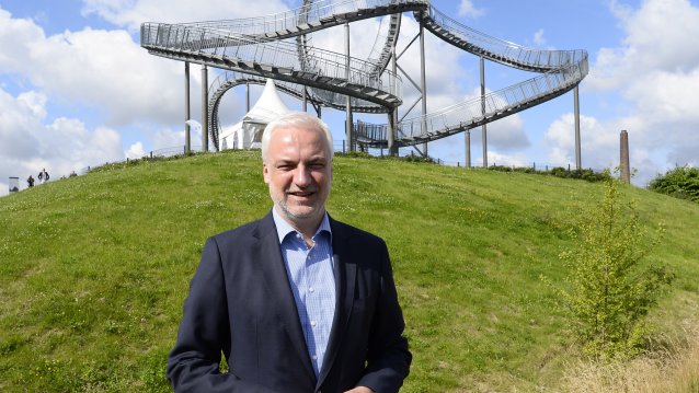 Minister Duin steht vor einer Achterbahn