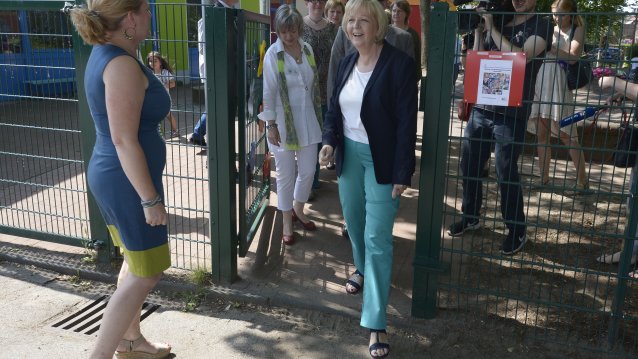 Ministerpräsidentin Hannelore Kraft durschreitet ein Tor zwischen zwei Kindergärten