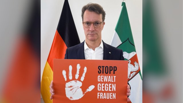 MP Wüst hält ein Schild hoch mit dem Text: Gewalt gegen Frauen