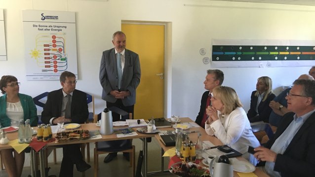 Bürgermeister Wilfried Roos steht und redet in einem Raum, seitlich sitzen Zuhörer