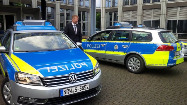 Bild mit 2 Polzeifahrzeugen und neongelben Streifen vor dem Innenministerium NRW