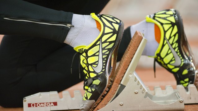Füße in gelben Sportschuhen sind auf einem Startblock