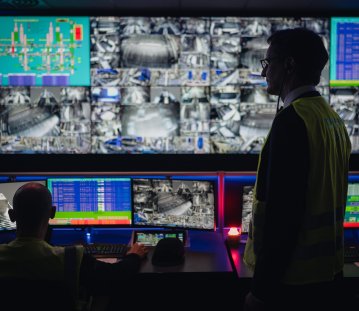 MP Wüst steht vor Monitoren eines Kontrollraums