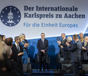 Mario Draghi steht auf der Bühne während das Publikum applaudiert