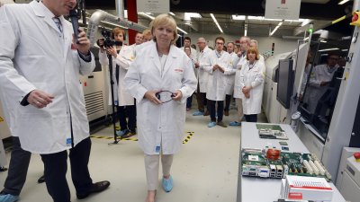 Ministerpräsidentin Kraft sthet bei ihrem Rundgang mit einem Mitarbeiter vor einem Tisch, auf dem ein PC-Mainboard offen liegt