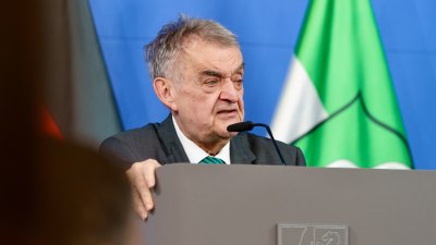 Minister Reul spricht an einem Rednerpult vor Flaggen