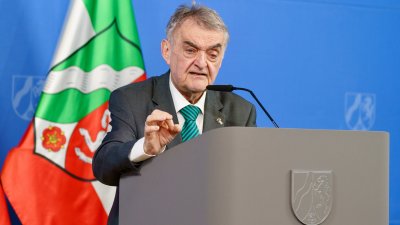 Minister Reul spricht an einem Rednerpult vor Flaggen