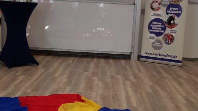 Auf einem großem Bildschirm läuft die Präsentation des Stadtsportbunds Bielefeld e.V.