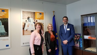 Staatssekretärin Milz in einem Büro der Landesvertretung mit einer Frau im schwarzem Anzug und roter Bluse und einem Mann im dunkelbleuem Anzug, weißem Hemd und blauer Krawatte.