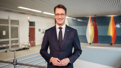 Ministerpräsident Hendrik Wüst steht vor einem leeren Schwimmbecken