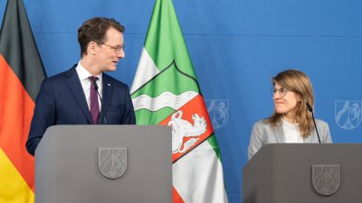 MP Wüst und Ministerin Schäffer stehen hinter ihren Rednerpulten und schauen sich an