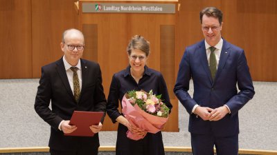 Ministerin Schäffer hält im Plenarsaal einen Blumenstrauß in der Hand, neben ihr der Landtagspräsident und der Ministerpräsident