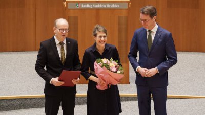 Ministerin Schäffer hält im Plenarsaal einen Blumenstrauß in der Hand, neben ihr der Landtagspräsident und der Ministerpräsident
