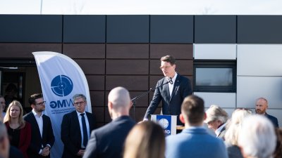 MP Wüst hält ein Grußwort vor einem Gebäude