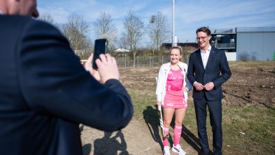 MP Wüst posiert mit einer Hockey-Spielerin