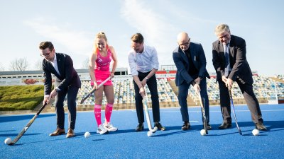 Eine Personengruppe posiert mit Hockeyschlägern