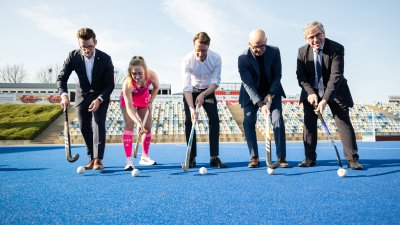 Eine Personengruppe posiert mit Hockeyschlägern