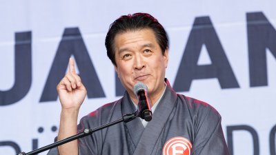 Ein Mann in traditionell japanischer Kleidung hält auf der Bühne einer Ansprache