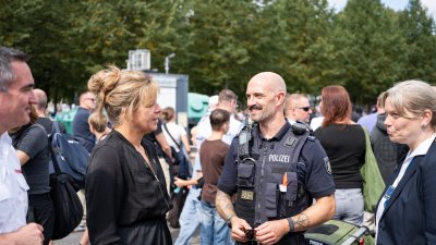 Wirtschaftsministerin Mona Neubaur unterhält sich mit einem Polizeibeamten