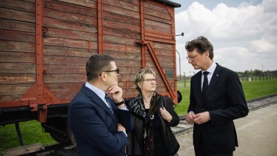 MP Wüst und die Antisemitismusbeauftragte Sylvia Löhrmann stehen mit dem Leiter der Führung vor einen Zugwagon