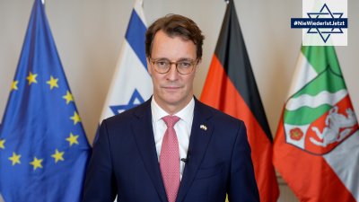 Ministerpräsident Hendrik Wüst steht vor Fahnen
