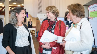 Drei Damen stehend im Gespräch.