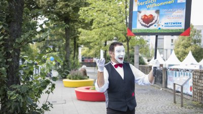 Ein Pantomimen-Darsteller mit einem Schild des Netzwerks Organspende