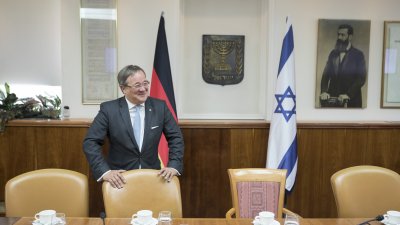 Herr Lascht steht am Tisch vor Flaggen und lacht