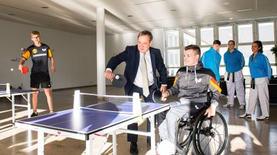 Armin Laschet spielt mit einem jungen Sportler im Rollstuhl Tischtennis.