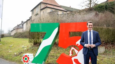 Ministerpräsident Hendrik Wüst steht vor einem großen Aufsteller mit der Zahl 75 in den Landesfarben