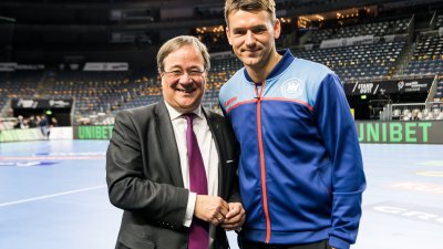 Ministerpräsident Armin Laschet mit einem Handballspieler auf der Spielfläche.