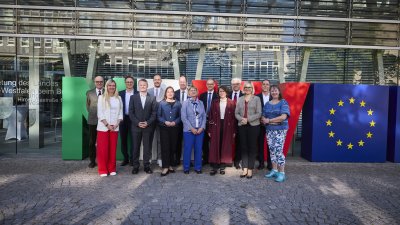 Eine Gruppe menschen steht vor riesigen Buchstaben N R und W und einem Würfel mit dem Europa-Logo