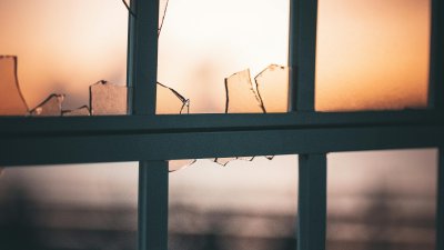 Eine Fenster mit zerbrochener Scheibe im Licht der Abenddämmerung