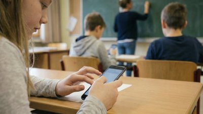 Schüler:innen sitzen im Klassenzimmer und spielen am Handy