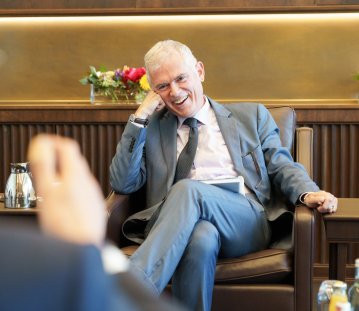 Besprechungssituation in einem festlichen Raum, der Doyen lacht