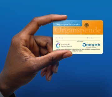 Eine Hand hält den orangenen Organspendeausweis