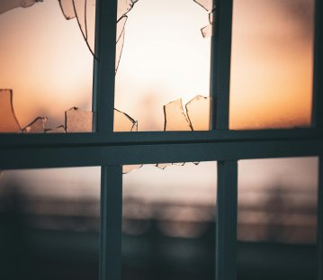 Eine Fenster mit zerbrochener Scheibe im Licht der Abenddämmerung